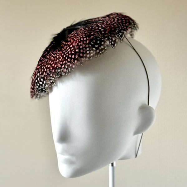 Rosie, a circular pillbox covered in rose-tinted guineafowl feathers, left